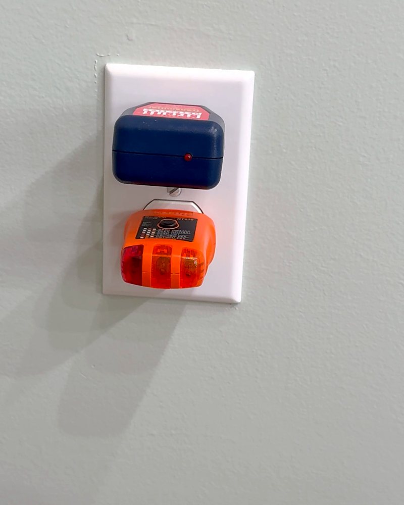 A circuit finder plugged into the top half of a receptacle and a receptacle tester in the bottom half